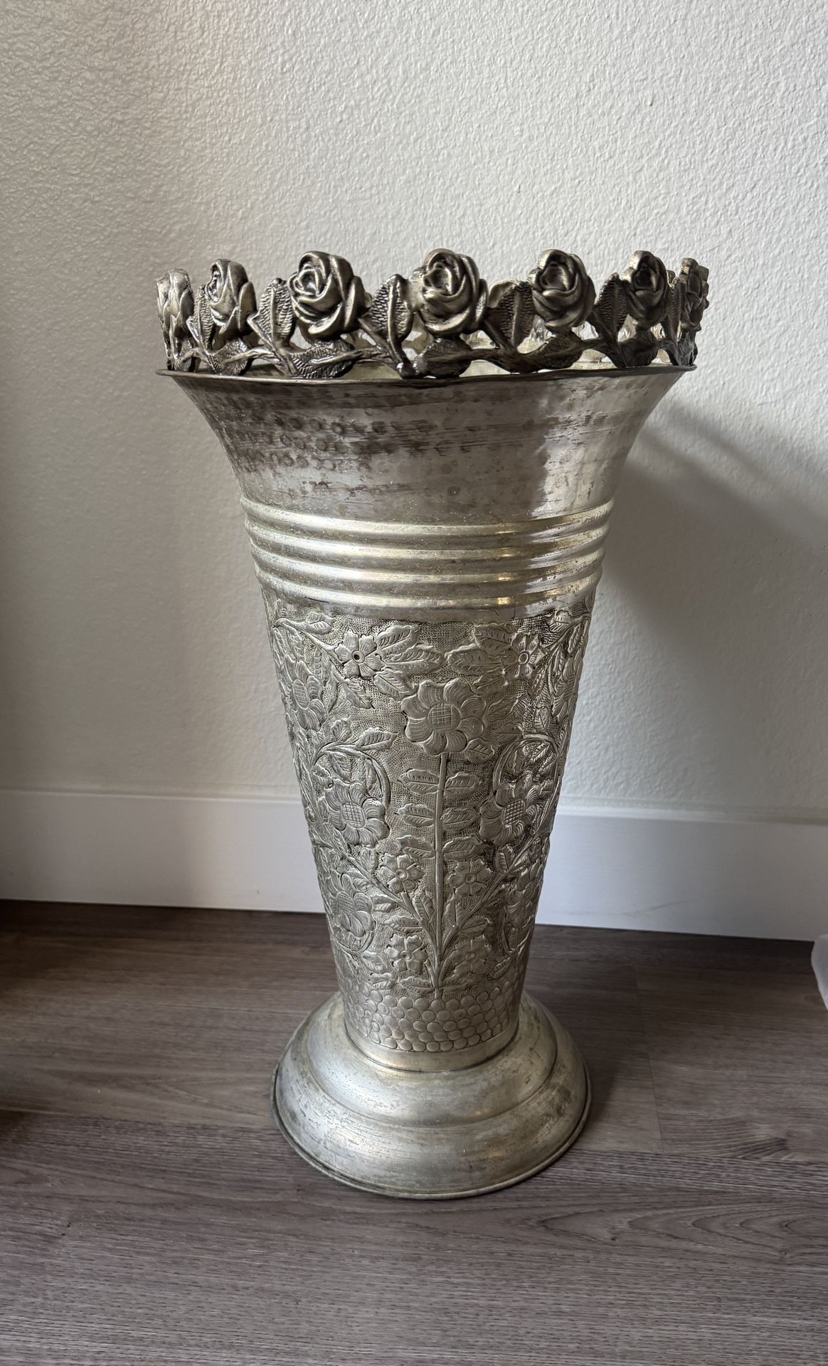 ornate silverplate or sterling silver repoussé vase with a floral rim and chased designs.