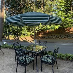 Nice aluminum glass table with four chairs, umbrella, and pads
