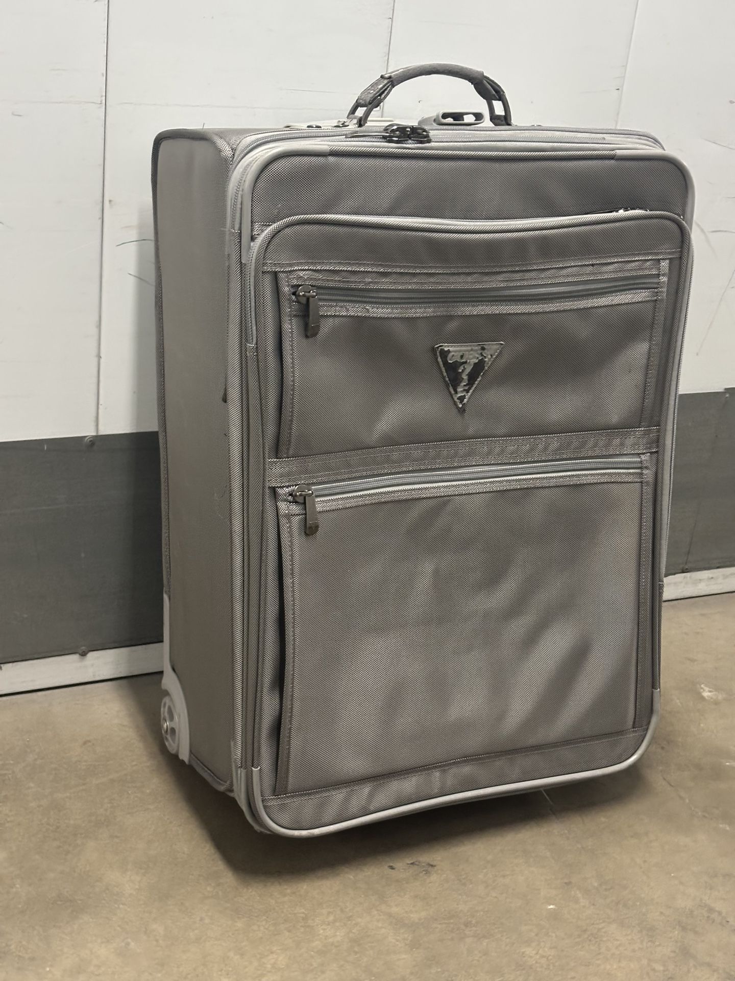 Silver Guess wheeled upright expandable medium trip suitcase.