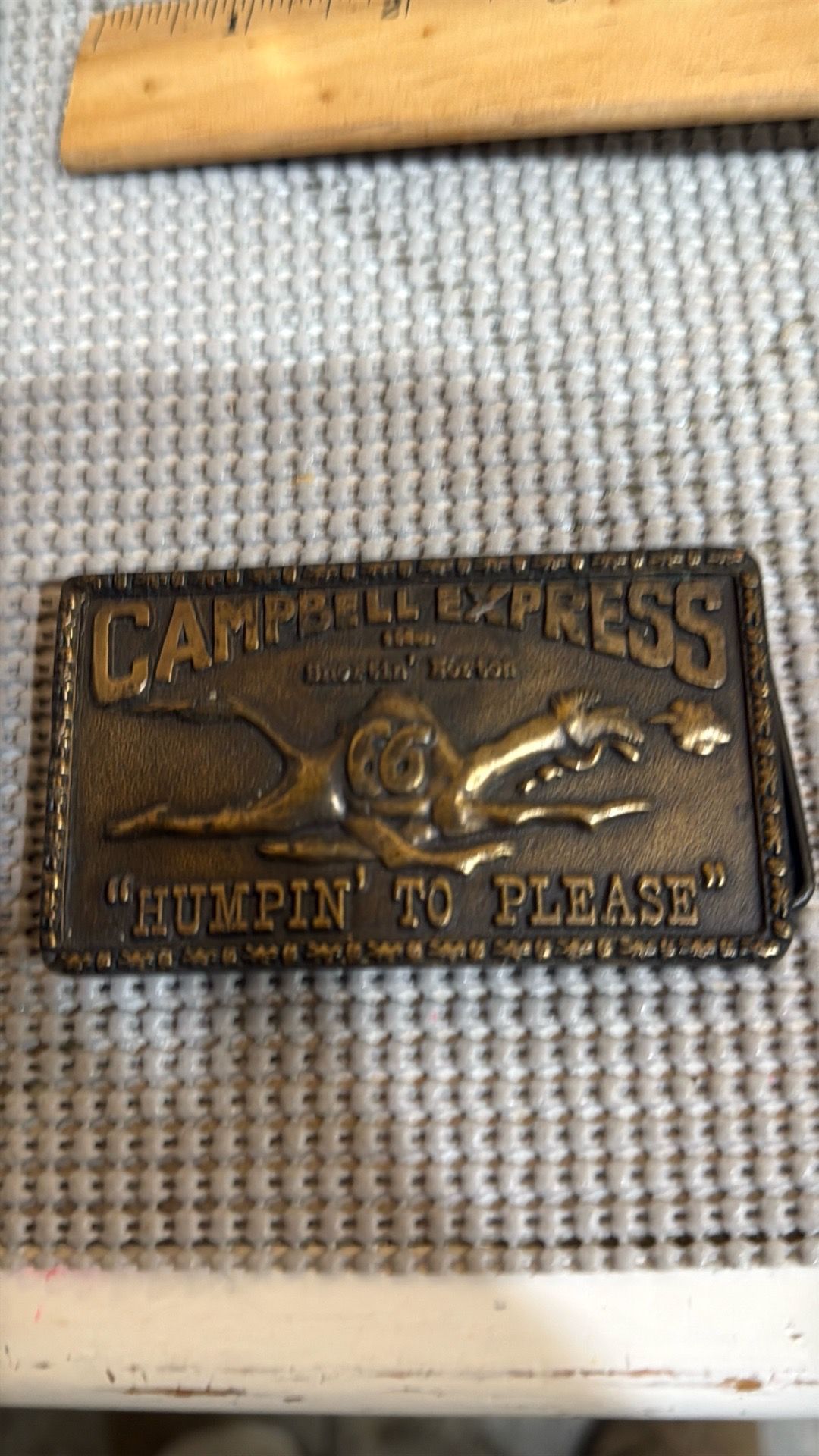 vintage brass belt buckle featuring the mascot and slogan of the Campbell 66 Express trucking company.
