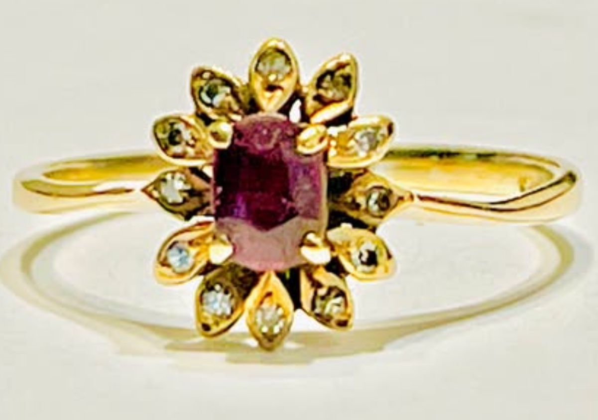 Beautiful Ruby center stone with diamonds set in a flower design set in 14k yellow gold size 7