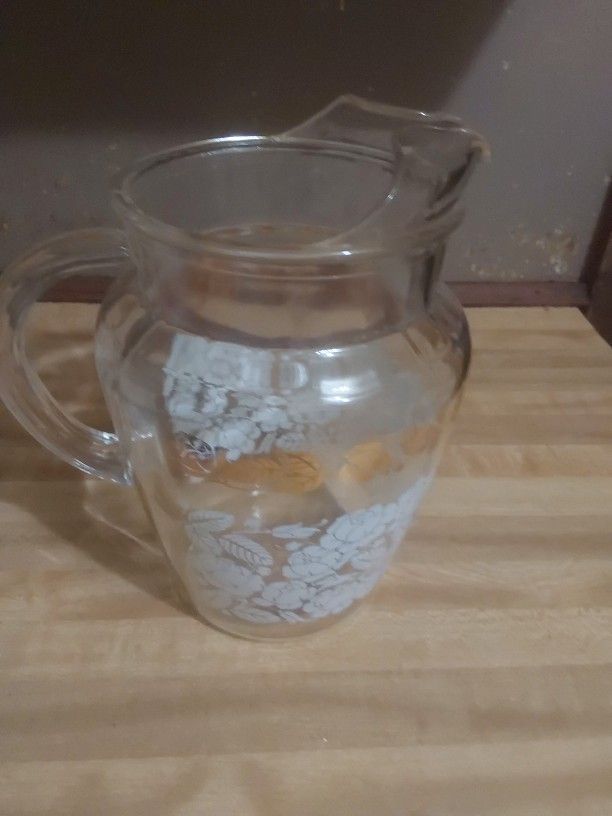 clear glass pitcher decorated with a white rose and gold floral pattern, often associated with vintage glassware