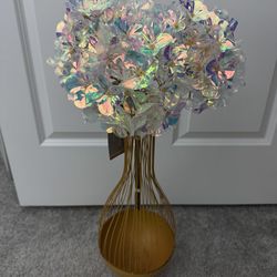 a new shiny bouquet of artificial flowers and a used metal vase