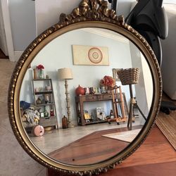 vintage round mirror featuring an ornate, gilded frame
