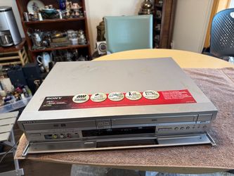 Versatile silver Sony RDR-VX500 DVD recorder and VHS VCR combo unit. This device has a front-loading VHS deck and a DVD tray with dual RW compatibilit