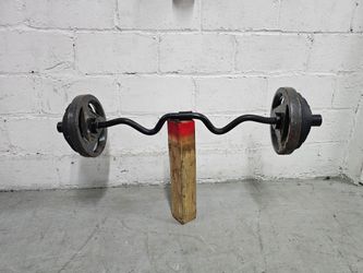100 Pounds total. Black EZ curl bar loaded with cast iron weight plates on both ends. Plates show surface rust and wear from regular use. Bar is in fu