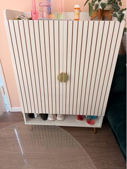 White shoe cabinet with gold accents