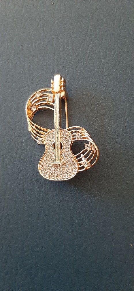 Guitar-shaped brooch with crystals.