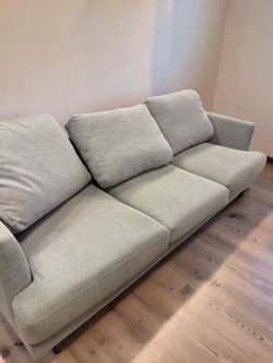 light gray fabric West Elm style  sofa features deep seats and low, wide arms for a modern look