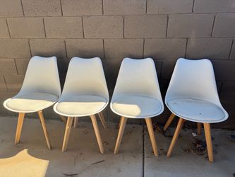 Four white chairs with wooden legs