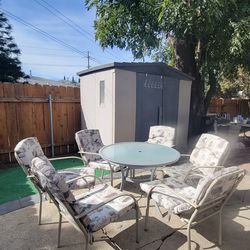 five-piece outdoor patio dining set featuring a round glass-top table and four chairs.