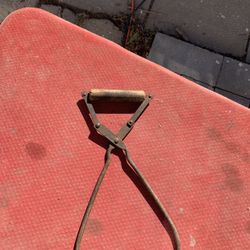 This is an antique or vintage pair of cast iron ice block tongs with a wooden handle. 