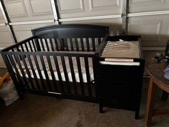 New crib never used. mattress wrapped in plastic.turns into toddler bed. with changing table attached