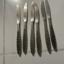 vintage International Silver Company dinner knives in the Lyon Romanesque stainless steel pattern.  Pattern: Romanesque, featuring an embossed scroll 