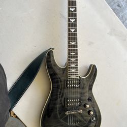 This item is a Schecter Omen Extreme-6 electric guitar in a See-Thru Black finish.  Body