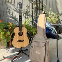 Vintage Baby Taylor Acoustic Guitar with strap, stand, and bag.
