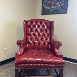 Elegant red leather armchair with tufted design and nailhead trim.