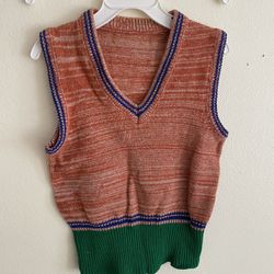 This is a children's knit vest in a retro style, also known as a waistcoat. • Fit and cut: It features a classic V-neck design, with ribbed cuffs and 