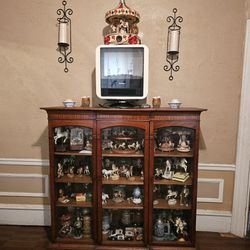 Glass wooden cabinet.
Electric fire heater Candle holders on wall with candles.
And horse collectibles And Other items collectibles inside