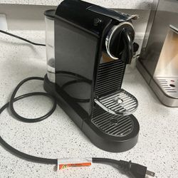 Nespresso coffee maker with milk frother next to it