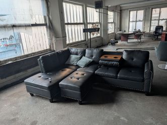 ​Like-New Black Faux Leather L-Shaped Sectional with Storage Ottoman & Cup Holders
