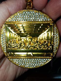 BEAUTIFUL GOLD TONED ROUND PENDANT FEATURING RHINESTONES AND THE SILHOUETTE OF THE LAST SUPPER.