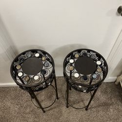 2 UMA Black Metal Plantstands With Many Colorful Ceramic Designs Surrounding The Plant Stand 