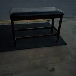 Very Working Condition dark wood bench featuring a padded black leather top.