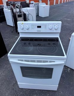 White Samsung electric range. Has a black glass cooktop with four burners. Oven has multiple racks. Samsung 30-in Glass Top 5 Elements 5.9-cu ft Self-