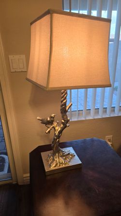 Silver resin table lamp featuring a sculptural tree branch base with a small decorative bird