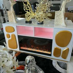 *White console table with electric fireplace and gold details* 