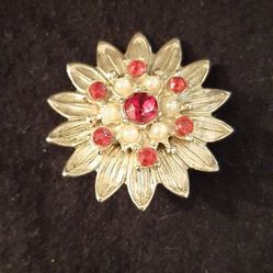 Gold tone brooch with red stones and pearl accents.