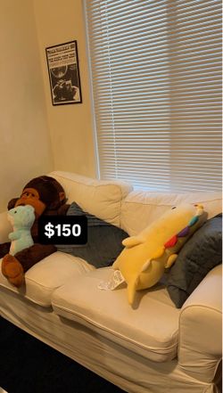 white ikea couch and two blue pillows