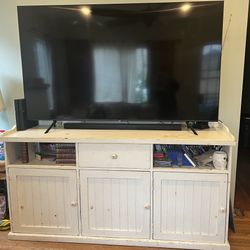 farmhouse-style white TV console table with drawers and cabinets for storage.