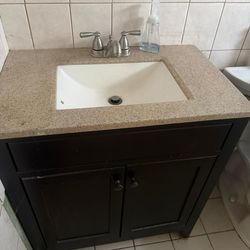 Dark brown bathroom vanity with sink and faucet