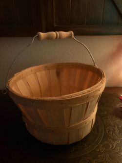 natural wood bushel basket featuring vertical wooden slats and a wire handle with a wooden grip