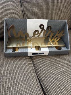 Brand new stocking holder that says “Merry” in gold metal