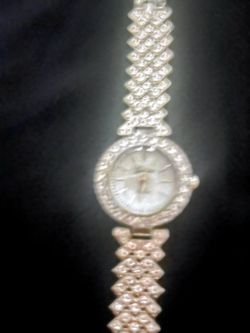 Sparkling women's dress watch has a silver-tone metal construction. The round case is surrounded by a bezel set with rhinestones. The decorative link 