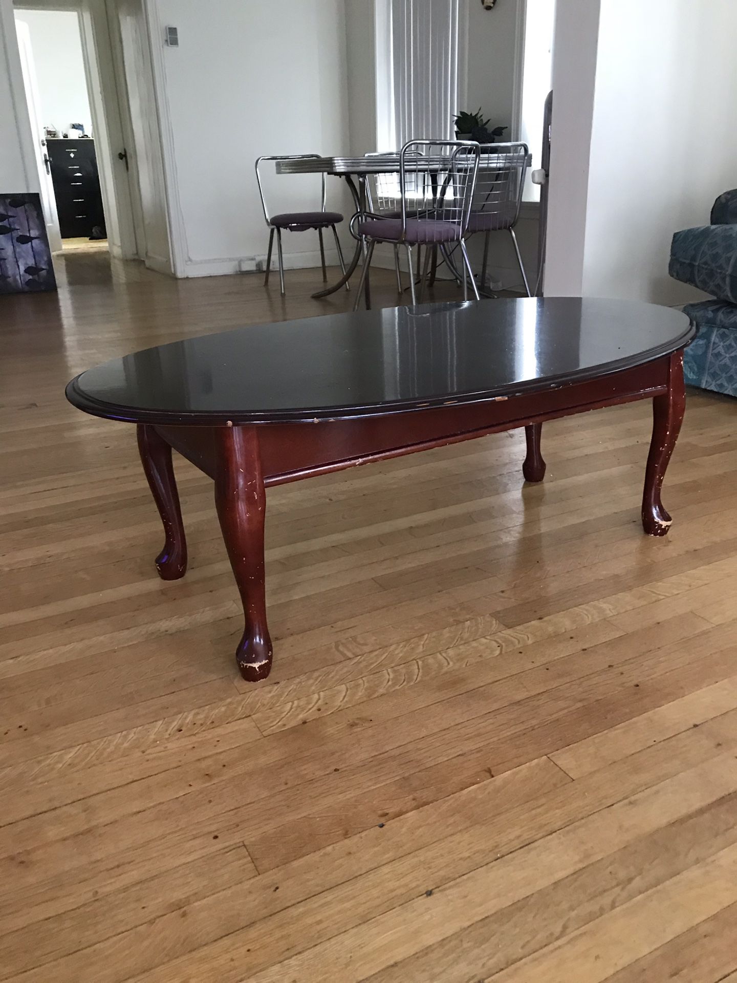 Oval coffee table, deep red wood color some wear and tear on the legs
