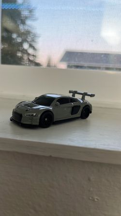 Gray die-cast toy sports car in good used condition. Features a detailed racing-style body with black wheels, tinted windows, and a large rear spoiler