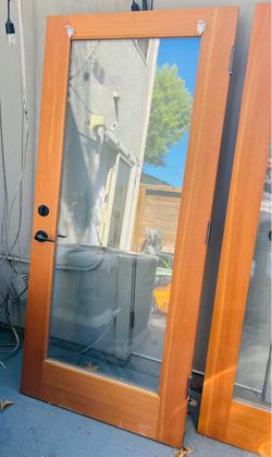 high-quality solid-wood, full-lite glass doors, likely Douglas fir or a similar vertical-grain softwood, with black lever/deadbolt hardware.