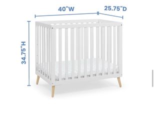 White mini crib with mattress