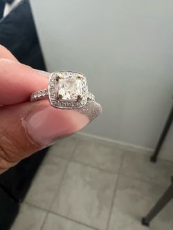 engagement ring crafted in solid 18K white gold, featuring a cushion-cut 1 ct center diamond accented with a halo and band of round diamonds, all with