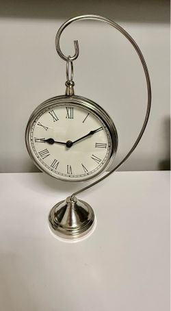 This Silver Metal Hanging Desk/Mantel Shelf Clock features a classic design with Roman numerals on its analog display, making it a stylish and functio