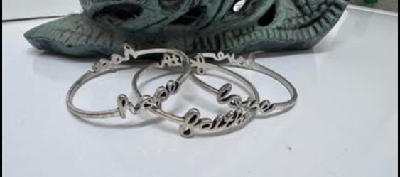 Premier Design Silver bangles feature cursive lettering faith", "hope"and "love"