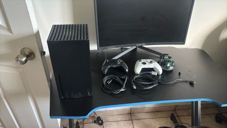 Xbox series x black with controllers and cords and a charging battery port