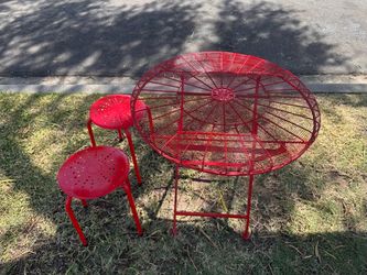 Red metal outdoor bistro set featuring a foldable table and two chairs.