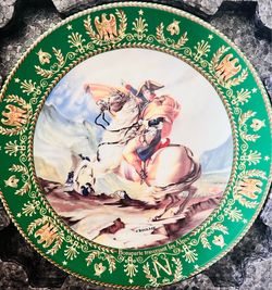 This is a decorative porcelain plate featuring the artwork "Bonaparte Traversant Les Alpes" (Napoleon Crossing the Alps).
