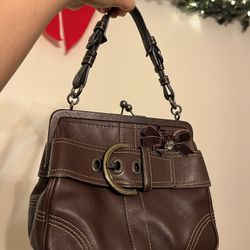 vintage Coach Soho Buckle Bag in brown leather with a kisslock closure and a velvet bow with a rhinestone center