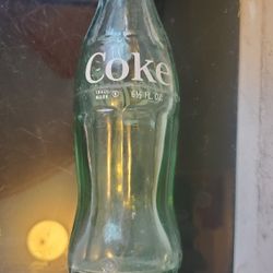 vintage Coca-Cola green glass bottle, specifically a 6.5 fl. oz. "hobbleskirt"